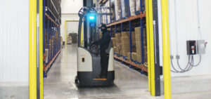 warehouse worker riding forklift through doorway